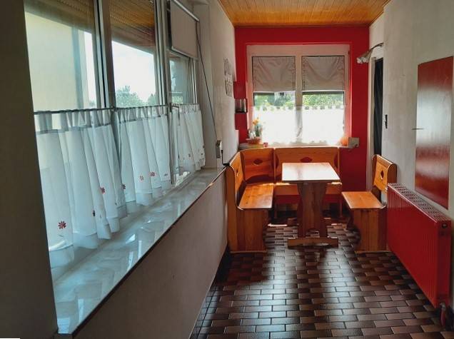Predaj rodinného domu, Bruck an der Leitha - Rodinný dom s dreveným posedením v kuchyni, červené steny a kachličkovaná podlaha.