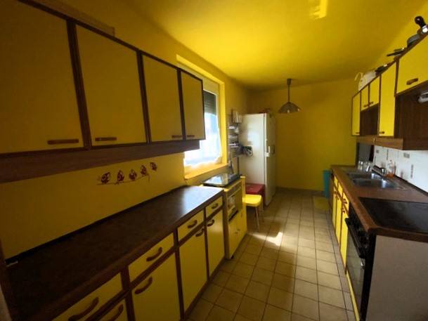 Predaj rodinného domu, Bruck an der Leitha - Kuchyňa v rodinnom dome so žltými stenami a skrinkami, priestor je svetlý a funkčný.