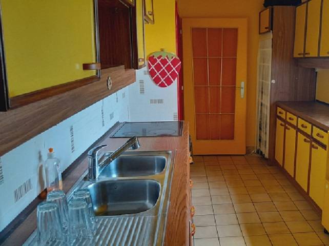 Predaj rodinného domu, Bruck an der Leitha - Kuchyňa v rodinnom dome so žltými skrinkami a nerezovým umývadlom.