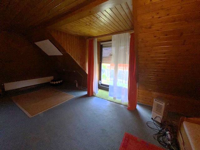 Predaj rodinného domu, Bruck an der Leitha - Podkrovná izba s dreveným obložením v rodinnom dome, závesy cez okno.