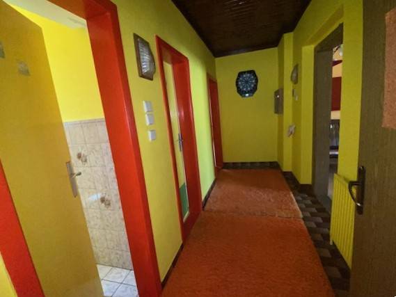 Predaj rodinného domu, Bruck an der Leitha - Chodba v rodinnom dome s jasnými žltými stenami a červenými dverami.