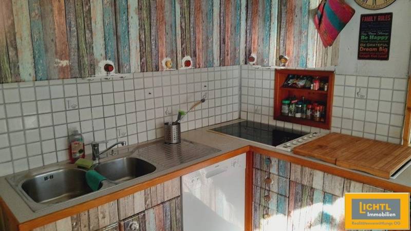 Predaj rodinného domu, Neusiedl am See - Kuchyňa v rodinnom dome s farebnými skrinkami a bielym obkladom.
