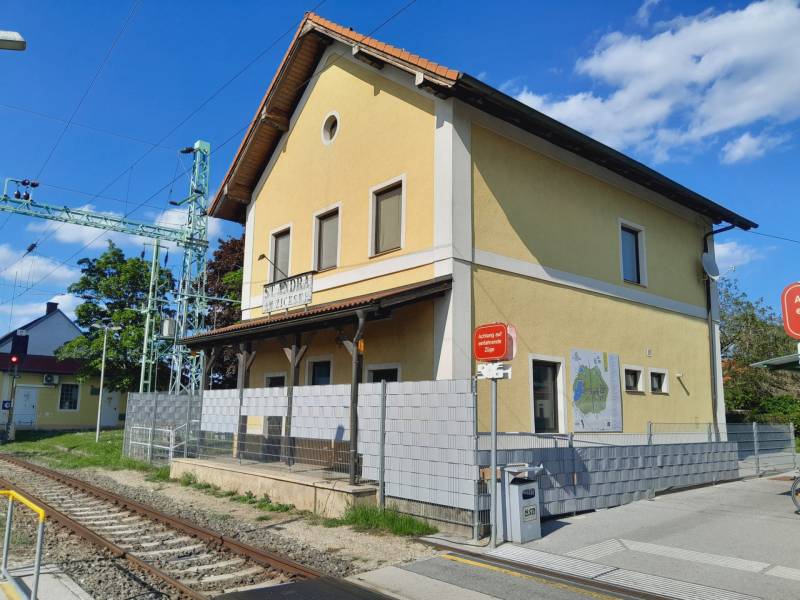 Prenájom obchodného priestoru, Neusiedl am See - Žltá budova železničnej stanice v St. Andrä am Zicksee s upozornením na vlaky.