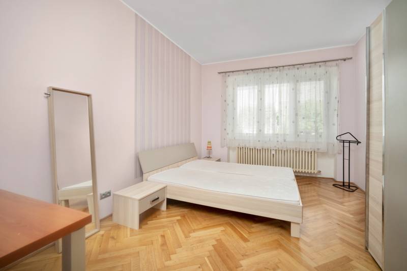 Vkusne zrekonštruovaný 3-izbový byt - Karadžičova ulica, Bratislava - Spálňa v 3-izbovom byte s posteľou, zrkadlom a drevenou podlahou.