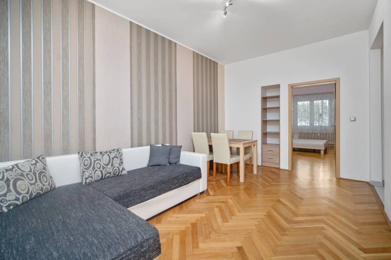 Vkusne zrekonštruovaný 3-izbový byt - Karadžičova ulica, Bratislava - Obývacia izba s oranžovým dreveným nábytkom, pohovkou a jedálenským stolom v 3-izbovom byte.