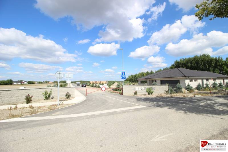 Luxusná veľkometrážna parcela za skvelú cenu Kvetoslavov,2480m2 - Brána na ulici vedie k pozemkom pre bývanie, na pozadí lesopark.