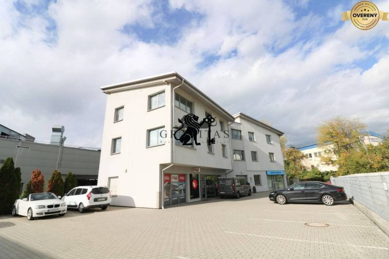 Samostatná kancelária 19,16 m2 - Lamačská cesta - Budova na ulici Lamačská cesta so zaparkovanými autami, kancelárie na prízemí, oblačné nebo.