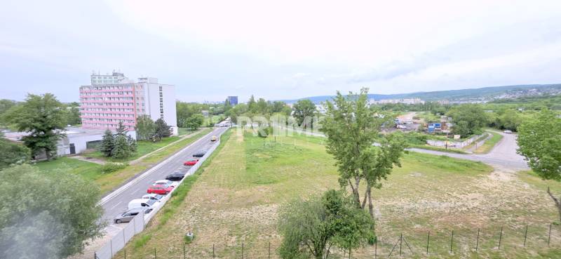BÝVAJ PRVÝ v 2i byte, DIAMNAT, BALKÓN, KLÍMA, PARKING, Rybničná ulica - Výhľad z Rybničnej ulice v Bratislave - Vajnory s parkoviskom a obytnými budovami.
