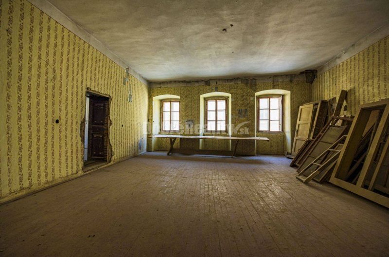 PREDAJ - investičná príležitosť - historocká budova Banská Štiavnica - - Interiér s podlahou s dreveným dekorom, oknami a starými tapetami v obchodných priestoroch.