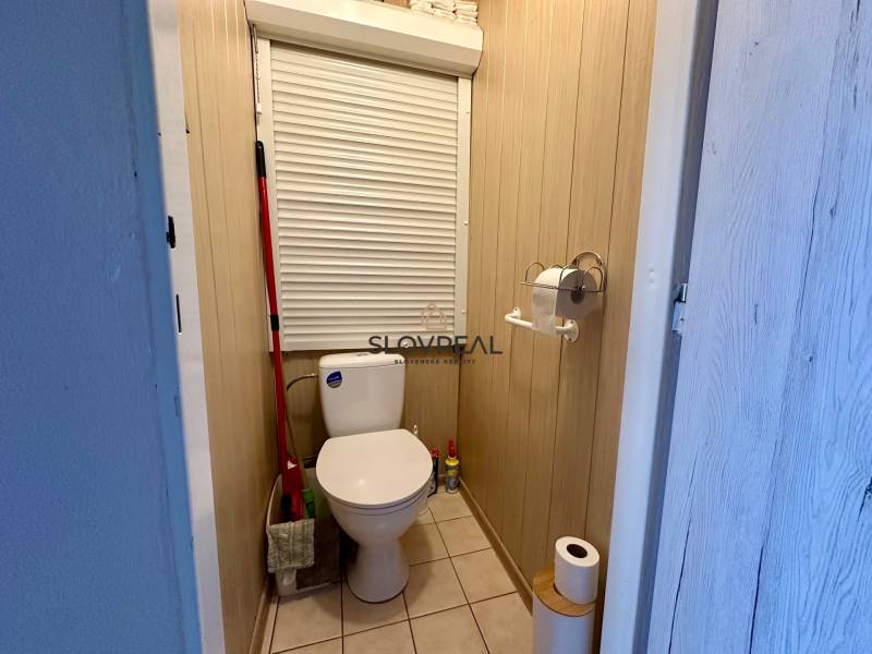 SLOVREAL -PREDAJ 3 IZBOVÝ BYT HANDLOVÁ  - Kúpeľňa s toaletou v 3-izbovom byte, obsahuje mop, toaletný papier a čistiace prostriedky.