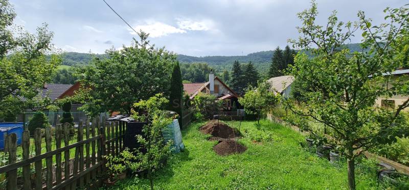 ✅ SLOVREAL Predaj rodinného domu kúsok od mesta Kremnica - Kopernica - Záber na rodinný dom s veľkou záhradou, trávnikom, a stromami v krásnom prírodnom prostredí.