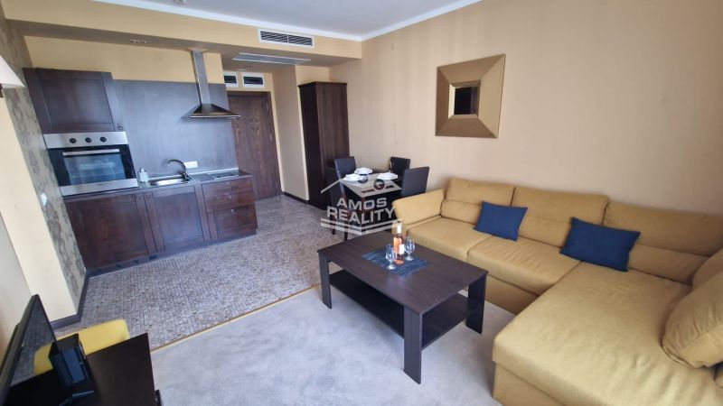 Predaj, 2 i apartmán 72 m2 + balkón výhľad na more, Burgas, BULHARSKO - Interiér rekreačného apartmánu s kuchyňou, sedačkou a jedálenským stolom v teplých farbách.