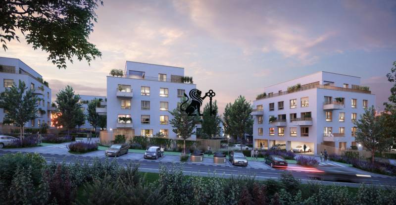 Na predaj 2-izbový byt s balkónom - A3 - Záber na večernú mestskú panorámu, budovy a cesty obklopené stromami.