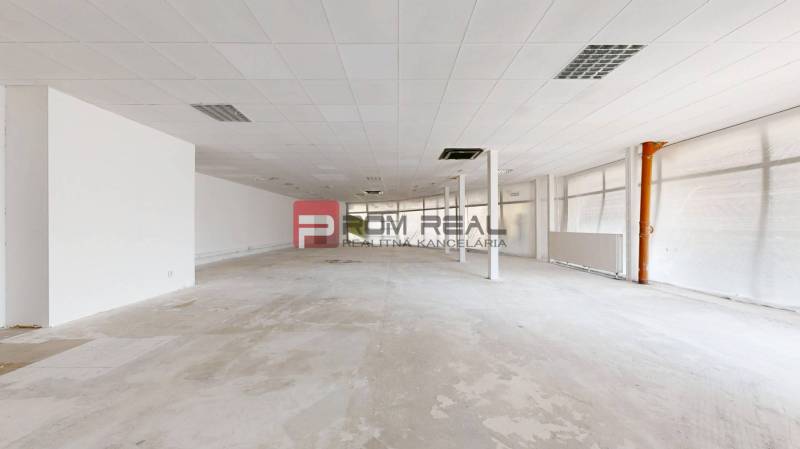 PREDAJ priestoru na frekventovanom mieste BRATISLAVA - Rozľahlé prázdne obchodné priestory s bielymi stenami a podhľadovým stropom.