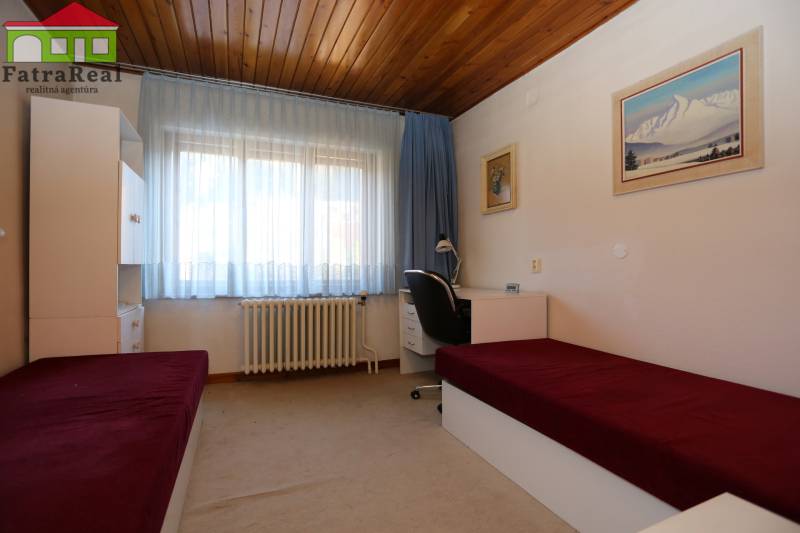 Rodinný dom po kvalitnej rekonštrukcii a prestavbe, Ľubochňa - Výhľad na izbu s dreveným stropom, posteľami a pracovným stolom v rodinnom dome.