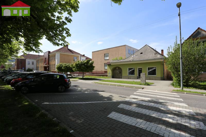 Rodinný dom v rekonštrukcii, Ružomberok - Na ulici Nám. A. Hlinku sa rodinný dom nachádza medzi zaparkovanými autami a zeleňou.