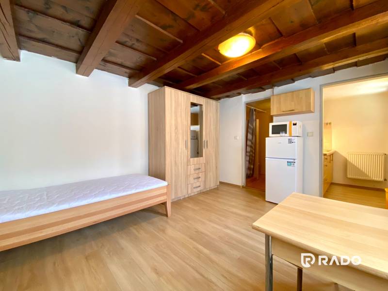 REZERVOVANÉ Garsónka 30m2 | Podunajské Biskupice - Garsónka s dreveným stropom, jednoduchým nábytkom a spotrebičmi, vrátane chladničky a mikrovlnky.