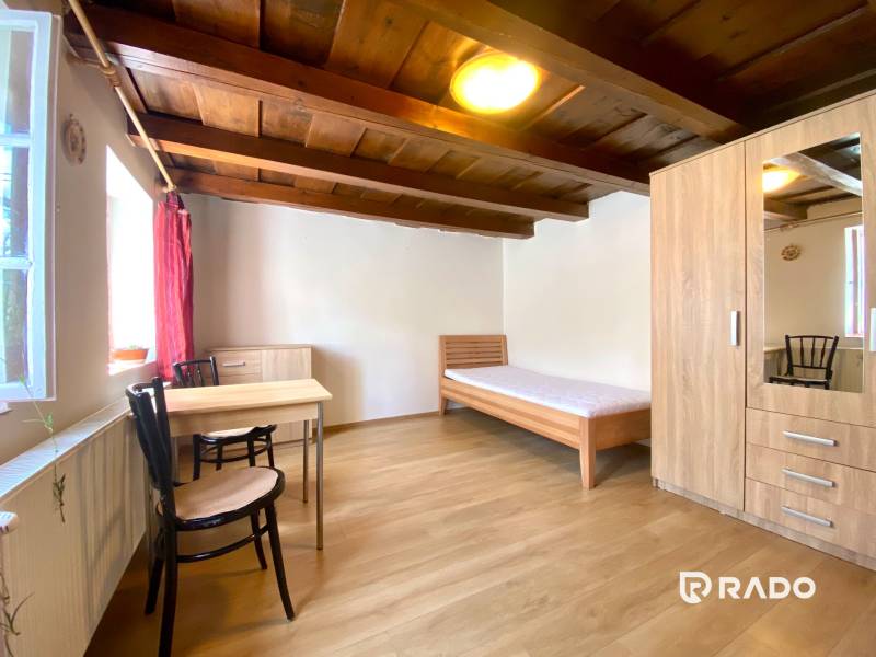 REZERVOVANÉ Garsónka 30m2 | Podunajské Biskupice - Garsónka so stolom, stoličkami, posteľou a skriňou v teplých drevených odtieňoch.