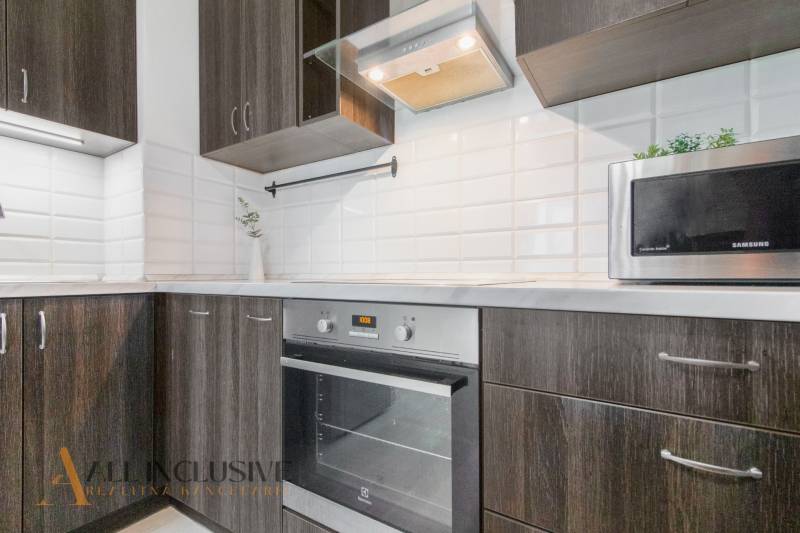 ALL INCLUSIVE REAL I KRÁSNY 2 IZBOVÝ BYT S BALKÓNOM GALANTA WEST - Kuchyňa v 2-izbovom byte so spotrebičmi a tmavým drevom, ozdobená bielymi kachličkami.