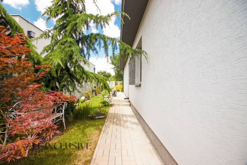 NA PREDAJ 4 IZBOVÝ ROD. DOM – NOVOSTAVBA, HORNÉ SALIBY - Bočný chodník pri rodinnom dome v Horných Salibách, obklopený zeleňou a kvetmi.