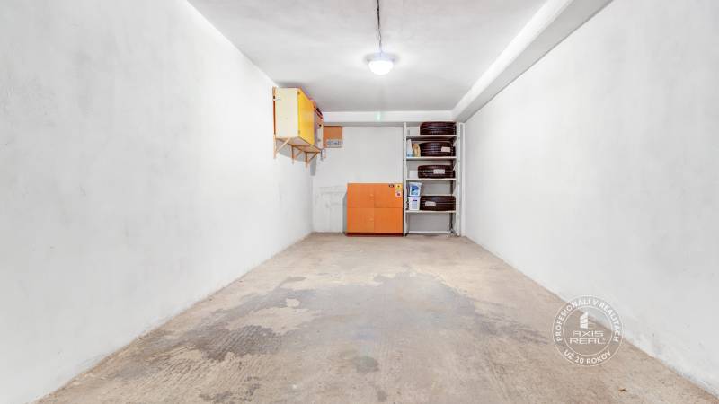 Garáž, Bratislava V. - Petržalka, Macharova ulica - Skladová miestnosť na ulici Macharova a garáže, biely interiér, regály a pneumatiky.