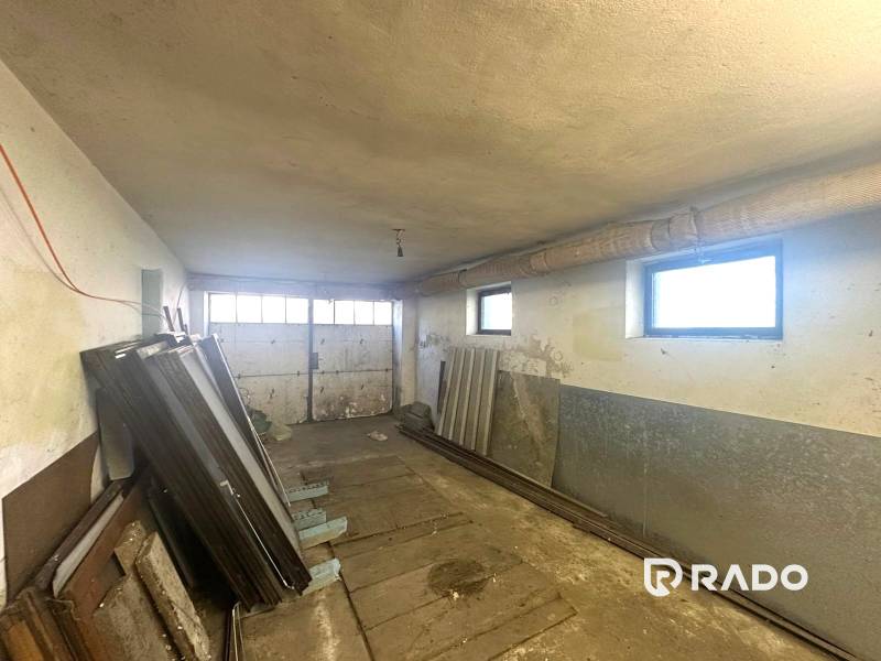 Na predaj Rodinný dom Drietoma – pozemok 745 m2  - Garáž v rodinnom dome s oknami, kovovými dverami a uskladnenými materiálmi.