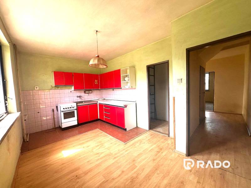 Na predaj Rodinný dom Drietoma – pozemok 745 m2  - Kuchyňa v rodinnom dome s červenými skrinkami a drevenou podlahou.