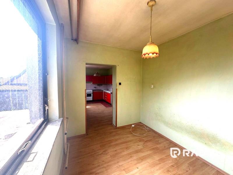 Na predaj Rodinný dom Drietoma – pozemok 745 m2  - Interiér s výhľadom na kuchyňu s červenými skrinkami v rodinnom dome.