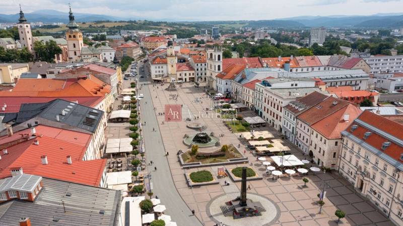 Kúpime VIDIECKÝ DOM s pozemkom v okolí Banskej Bystrice. - Na obrázku je námestie v Banskej Bystrici s reklamou na 1-izbový byt.