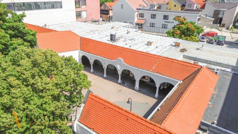 NA PRENÁJOM OBCHODNÝ PRIESTOR V CENTRE,DUNAJSKÁ STREDA - Obchodné priestory v Dunajskej Strede s oblúkmi a červenými strechami pri zástavbe.