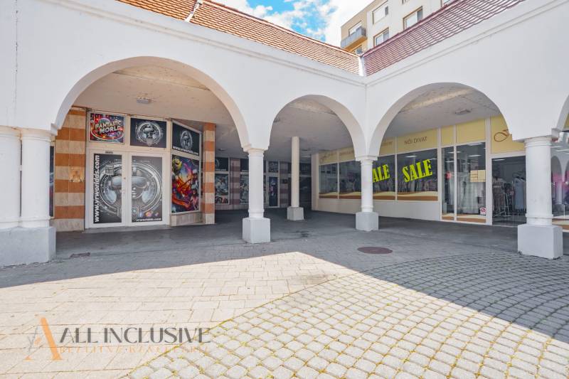NA PRENÁJOM OBCHODNÝ PRIESTOR V CENTRE,DUNAJSKÁ STREDA - Obchodné priestory v Dunajskej Strede s oblúkovými arkádami a reklamou na zľavy.
