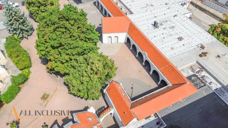 NA PRENÁJOM OBCHODNÝ PRIESTOR V CENTRE,DUNAJSKÁ STREDA - Letecký pohľad na obchodné priestory s červenými strechami, zeleňou a stromami v Dunajskej Strede.