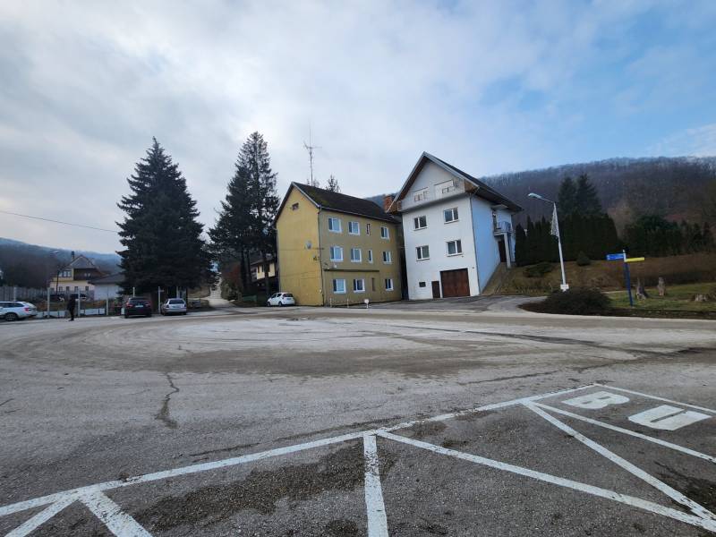 Stavebný pozemok 1001 m2 - Budovy pri ceste na pozemkoch pre bývanie v Majdane, Horné Orešany, obklopené stromami.