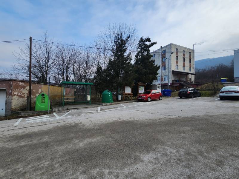 Stavebný pozemok 1001 m2 - Parkovisko na ulici Majdan v Horných Orešanoch, obklopené stromami a obytnými budovami.