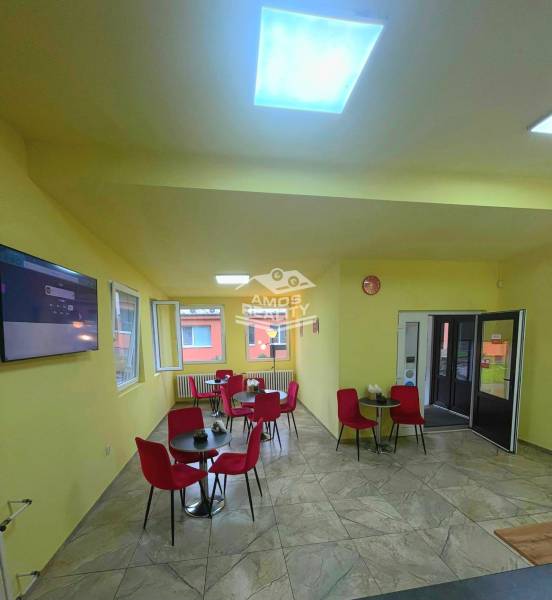 Predaj/odstúpenie zabehnutej gastro prevádzky s kuchyňou, Bratislava 2 - Gastro priestory s červenými stoličkami, žltými stenami a televíziou na stene.