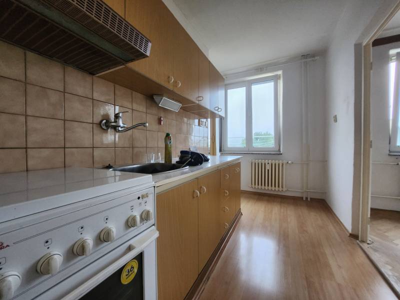 3-izbový byt Piešťany - Kuchyňa v 3-izbovom byte s drevenými skrinkami a bielou rúrou.
