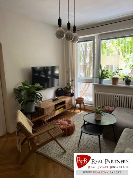 Prenájom 4izb-byt, Bratislava-Karlova Ves - Obývacia izba so sedačkou, TV a izbovými rastlinami v 4-izbovom byte.