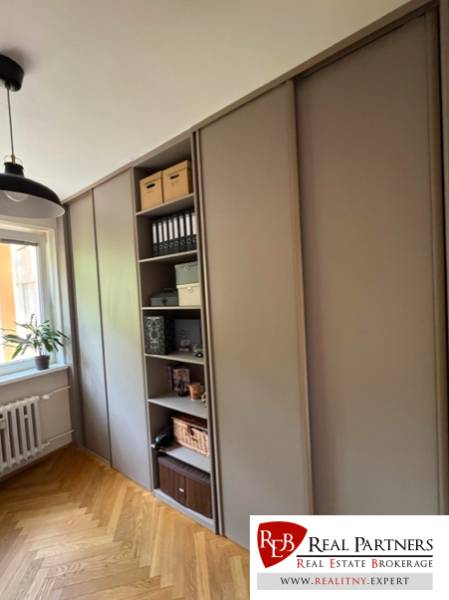 Prenájom 4izb-byt, Bratislava-Karlova Ves - Šatník v 4-izbovom byte s drevenou podlahou a poličkami na úložné priestory.