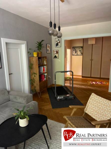 Prenájom 4izb-byt, Bratislava-Karlova Ves - Obývacia izba so svetlým nábytkom, rastlinami, dekoráciami a bežeckým pásom v 4-izbovom byte.