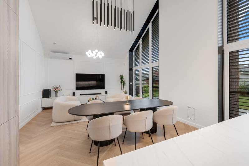 THE HOME ︱ PREDAJ - designový 5-izbový rodinný dom v Chorvátskom Grob - Obývačka v rodinnom dome s veľkým stolom, kreslami a televízorom na stene.