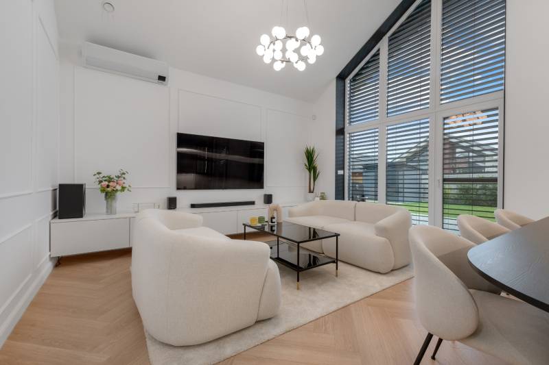 THE HOME ︱ PREDAJ - designový 5-izbový rodinný dom v Chorvátskom Grob - Obývačka v rodinnom dome s bielym nábytkom, veľkými oknami a televízorom na stene.