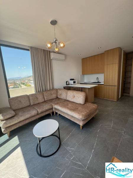 Ksamil – luxusné zariadené apartmány v Maledivách Európy - Obývacia izba rekreačného apartmánu s rohovou sedačkou, výhľadom a kuchynským kútom.