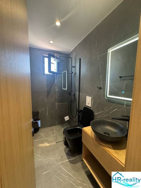 Ksamil – luxusné zariadené apartmány v Maledivách Európy - Kúpeľňa Rekreačného apartmánu so sprchovým kútom, čiernym umývadlom a osvetleným zrkadlom.