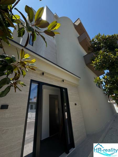 Ksamil – luxusné zariadené apartmány v Maledivách Európy - Fasáda rekreačného apartmánu v Ksamil, obklopená zeleňou a jasnou oblohou.