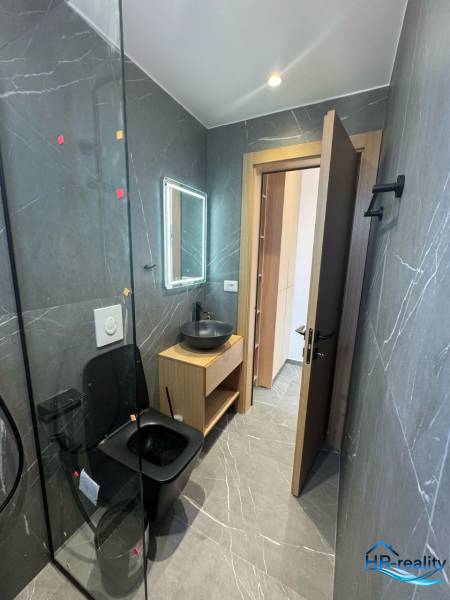 Ksamil – luxusné zariadené apartmány v Maledivách Európy - Kúpeľňa v rekreačnom apartmáne s čiernym sanitárnym zariadením a dreveným nábytkom.