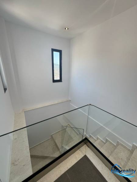 Ksamil – luxusné zariadené apartmány v Maledivách Európy - Schodisko v Rekreačnom apartmáne s veľkým skleneným zábradlím a úzkym oknom.