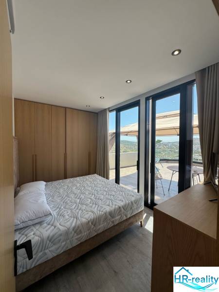 Ksamil – luxusné zariadené apartmány v Maledivách Európy - Spálňa v rekreačnom apartmáne s výhľadom z balkóna, drevený nábytok a posteľ.