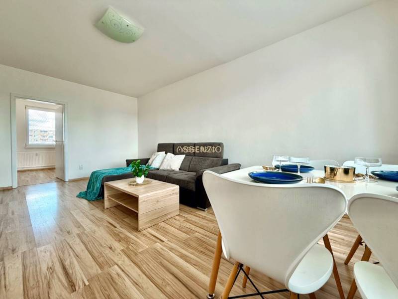 - EXKLUZÍVNE - PREDAJ - 3,5 IZBOVÝ BYT - LEVICE - Obývacia izba v 4-izbovom byte s pohovkou a jedálenským stolom so stoličkami.