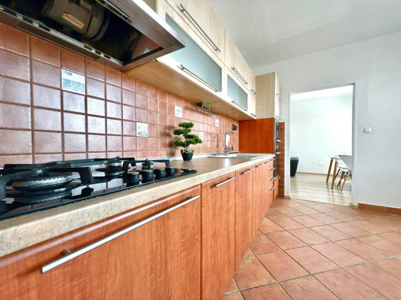 - EXKLUZÍVNE - PREDAJ - 3,5 IZBOVÝ BYT - LEVICE - Kuchyňa v 4-izbovom byte s plynovým sporákom a hnedými keramickými obkladačkami.