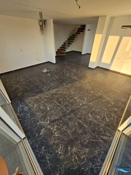  Albánsko, Sarandë – luxusné novostavby apartmánov v prvom rade - Rekreačný apartmán s tmavou dlážkou, bielymi stenami a schodiskom.